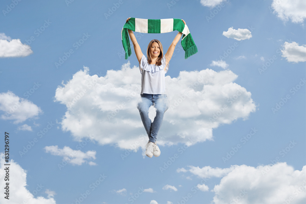 Young woman cheering with a green and white scarf from the clouds Young woman cheering with a green and white scarf from the clouds