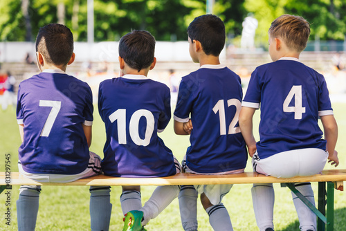 Multiethnic Kids in Soccer Jersey Shirts Sitting on Substitute Wooden Bench. School Children at Sports Tournament. Boys Play Soccer Game During Youth Soccer League