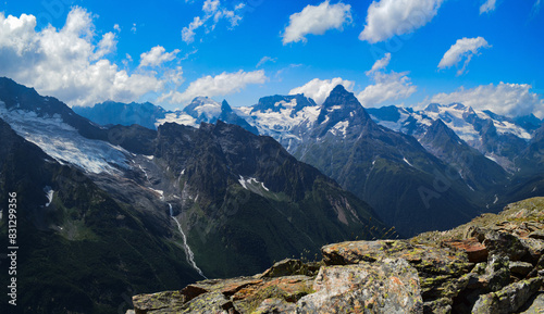 Beautiful peaks of the Western Caucasus, Dombai region, on a sunny summer day. Mountains covered with snow and glaciers. Panoramic view.
