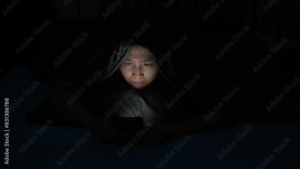 Young Woman Addicted to Social Media, Lying in the Dark Bedroom, Struggling with Insomnia and Strained Eyes from Nighttime Scrolling and Online Shopping Young Woman Addicted to Social Media, Lying in the Dark Bedroom, Struggling with Insomnia and Strained Eyes from Nighttime Scrolling and Online Shopping