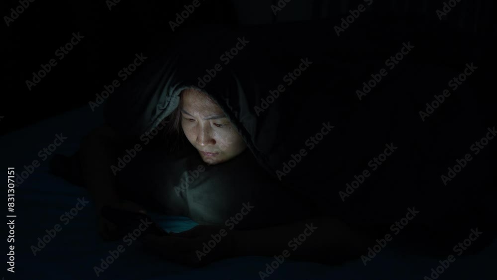 Young Woman Addicted to Social Media, Lying in the Dark Bedroom, Struggling with Insomnia and Strained Eyes from Nighttime Scrolling and Online Shopping Young Woman Addicted to Social Media, Lying in the Dark Bedroom, Struggling with Insomnia and Strained Eyes from Nighttime Scrolling and Online Shopping
