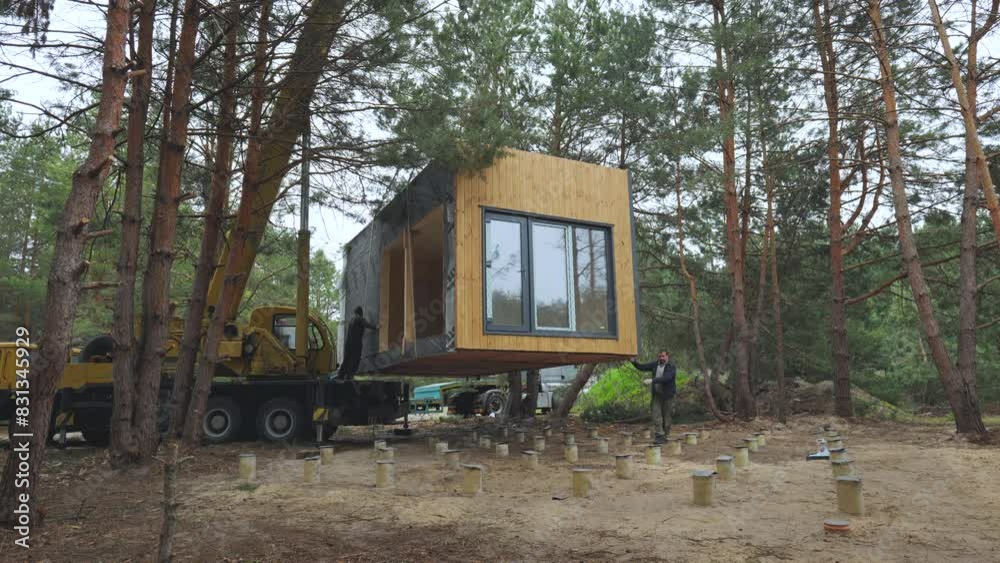 Installation of a Modern Prefabricated Cabin in a Forested Area During Early Spring Installation of a Modern Prefabricated Cabin in a Forested Area During Early Spring