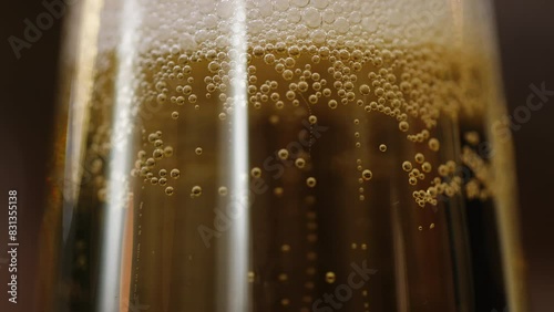 Close up of rising oxygen bubbles topped by layer of froth in flute glass filled with sparkling white wine. A Festive alcoholic drink for celebrating special occasions in refined atmosphere.