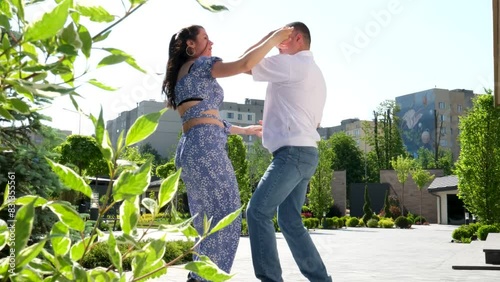 Couple dancing outdoors bachata professional dance in park. Blue summer suit for a girl, man in a white shirt and jeans photo