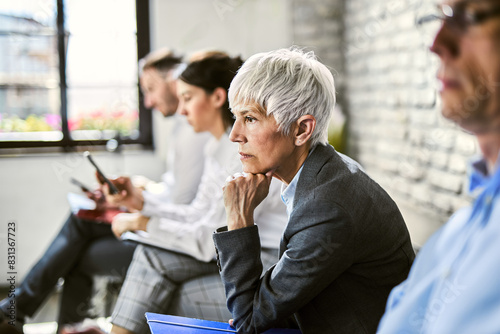 Mature  businesswoman feeling worried while waiting for job interview with other candidates.
