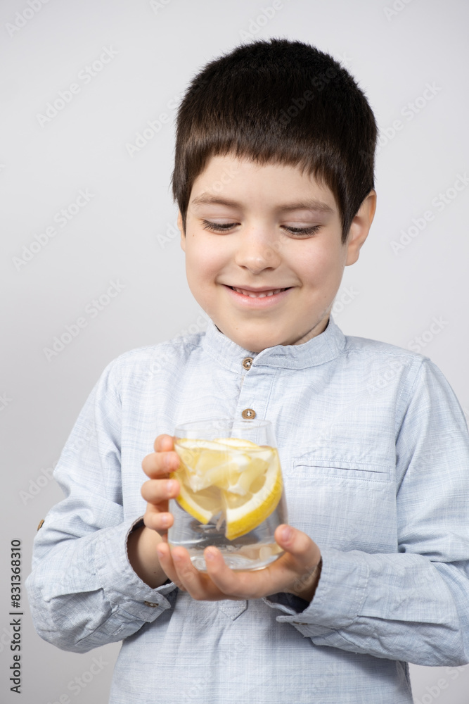 Happy six-year-old boy holding a glass of lemon water in his hands. Happy six-year-old boy holding a glass of lemon water in his hands.