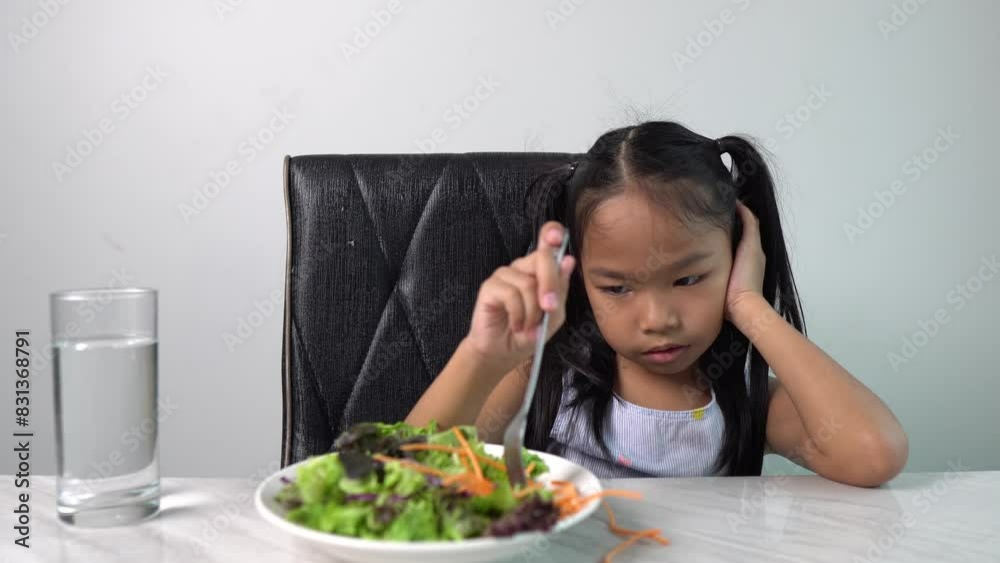 An Asian Girl Refusing to Eat Vegetables at Dinner, Illustrating the Challenge of Encouraging Healthy Eating Habits in Children An Asian Girl Refusing to Eat Vegetables at Dinner, Illustrating the Challenge of Encouraging Healthy Eating Habits in Children