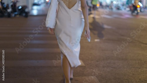 A slender woman in a white dress crosses the street photo