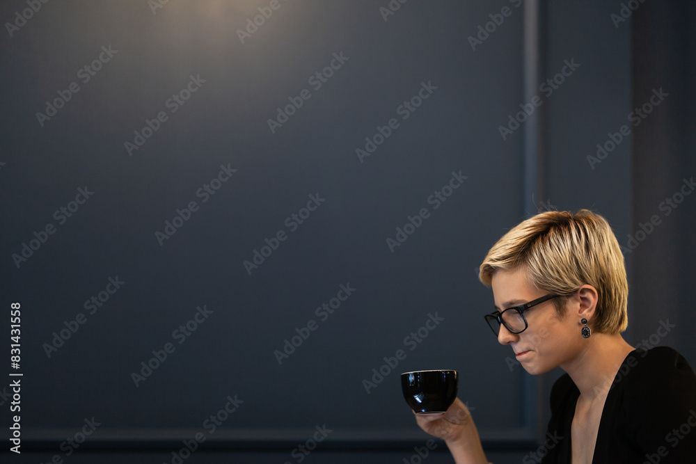 A thoughtful businesswoman enjoys a cup of coffee in a serene office setting, reflecting a moment of peace during a busy workday.