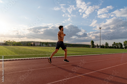 A man runs on a track with a cloudy sky in the background
