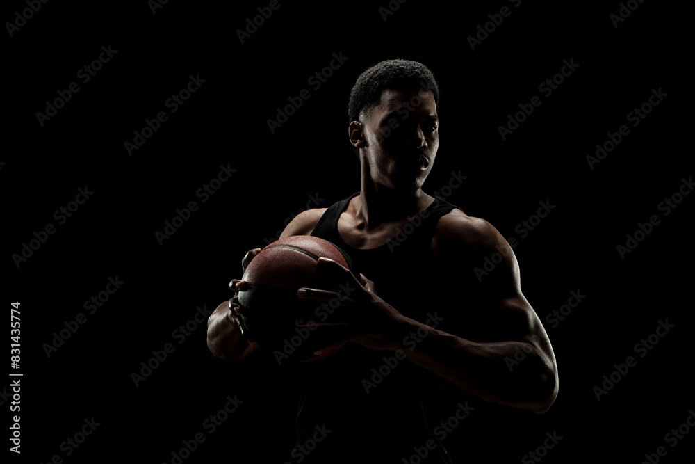 Basketball player holding a ball against black background. Serious concentrated african american man. Basketball player holding a ball against black background. Serious concentrated african american man.
