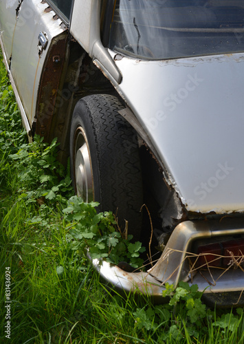 Classic French car without fenders rusting in a meadow