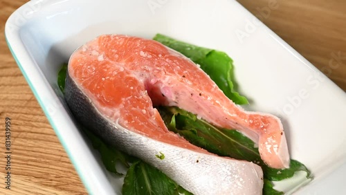 Woman hands salting fresh raw salmon steak before baking