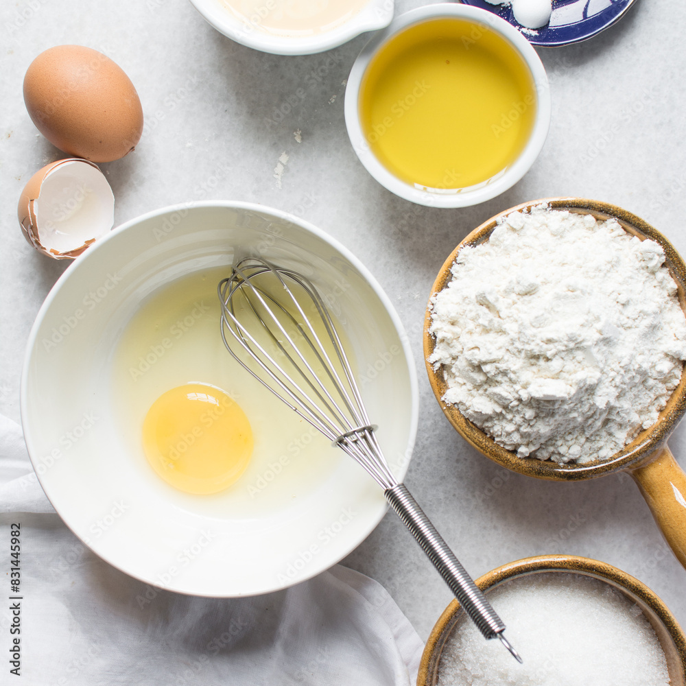 Overhead view of organic raw eggs in a white mixing bowl for baking and cooking, flatlay of egg in a white ceramic bowl Overhead view of organic raw eggs in a white mixing bowl for baking and cooking, flatlay of egg in a white ceramic bowl