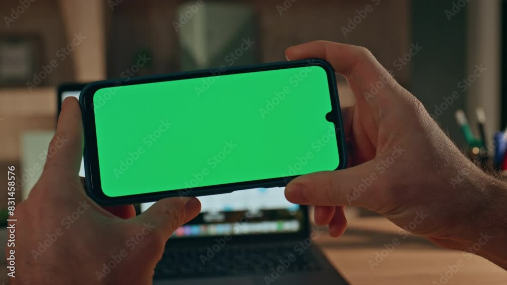 Unknown man watching green screen smartphone video in evening home close up.
