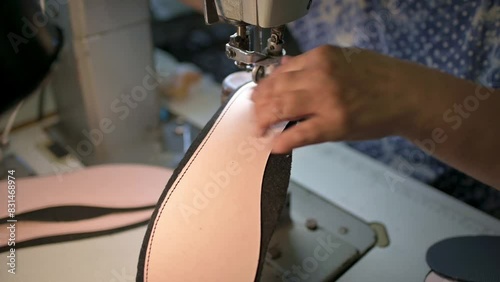 Male shoemaker works on sewing machine at the private workshop. Male bootmaker is sewing fabrics for shoes in shoe workshop. Shoe making process photo