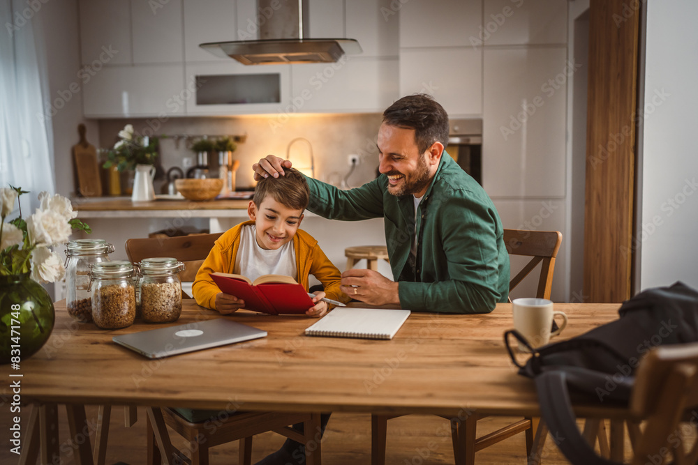 Son read a book and have fun while spend time with his father at home