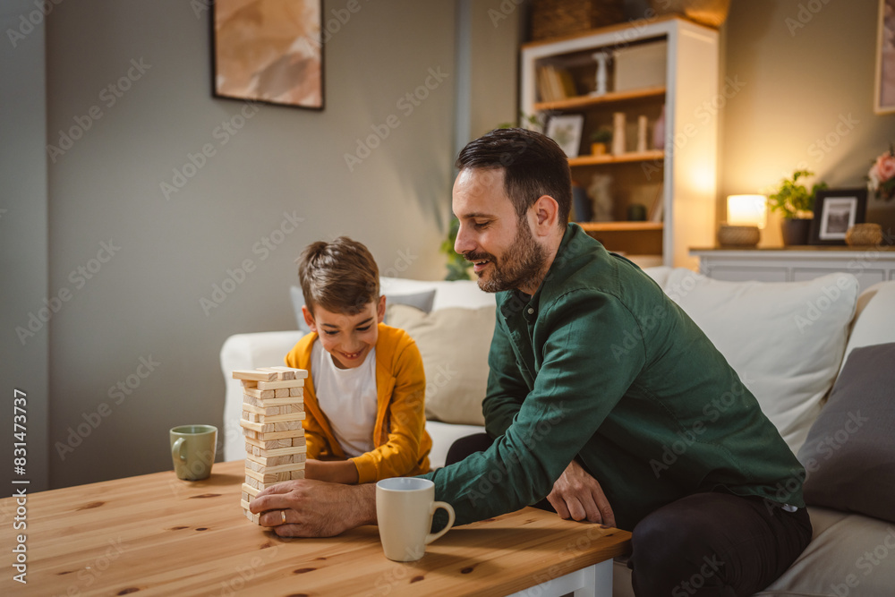 Father with cup of hot drink and son play board game together at home Father with cup of hot drink and son play board game together at home