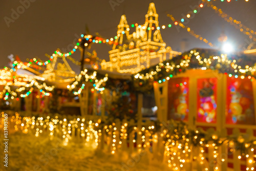 Defocused colorful houses on Christmas Fair in winter with lots of lights and bokeh on snowy evening