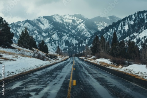 Empty road leads towards majestic snowcovered mountains under a cloudy sky