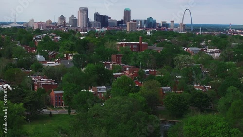 Reveal arerial shot of St. Louis skyline with the iconic gateway arch, set against a backdrop of greenery and residential neighborhoods. Urban architecture of missouri's downtown area photo