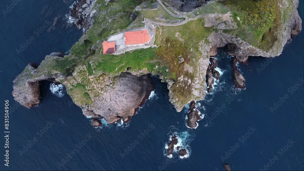 Aerial top view of San Juan de Gaztelugatxe with its hermitage, beaten by the waves of the blue sea. Famous natural and touristic landscape of Biscay, in the Basque Country