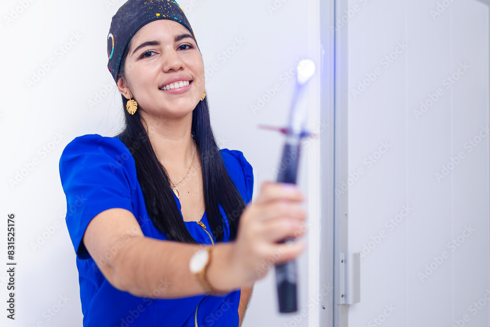 Young professional dentist, happy and smiling, holding a photopolymerizer.
Young professional dentist, happy and smiling, holding a photopolymerizer.