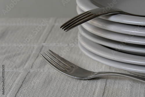 bright forks and white plates stacked on a table with white tablecloth