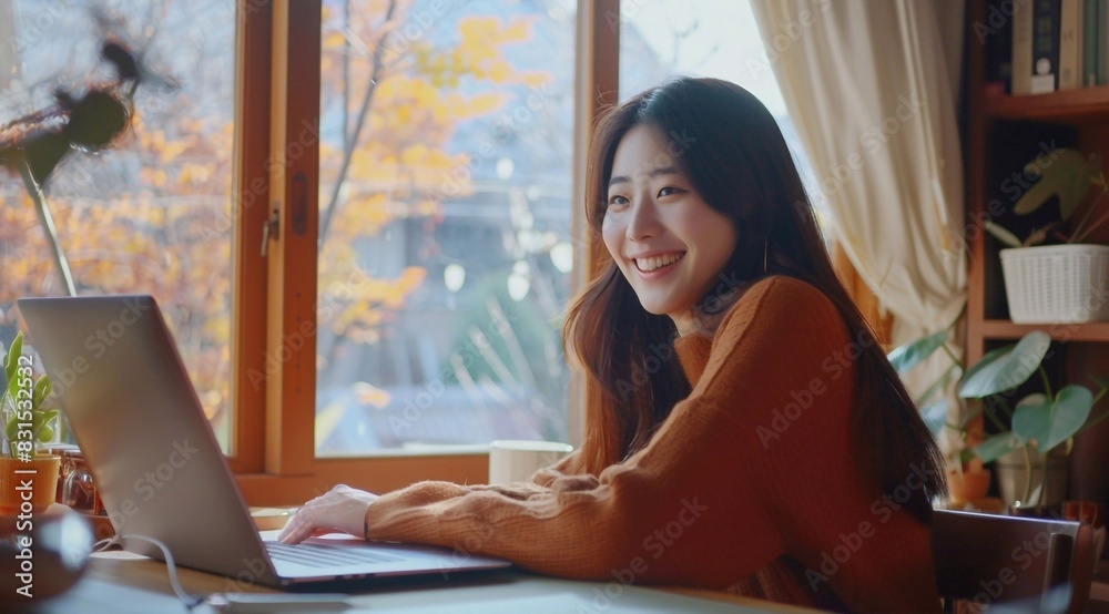 © yj - A smiling korean young woman sitting at her desk, working on her laptop in a home office room with a window. a calm and tranquil mood for working. generative AI