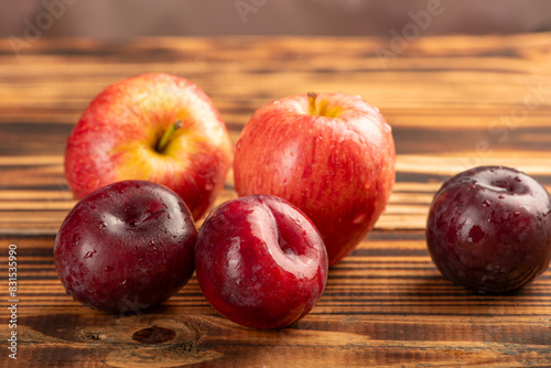 Apples and plums on rustic wood, selective focus.