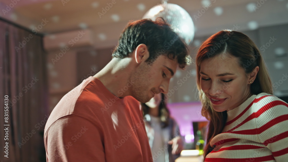 Relaxed couple enjoy disco party dancing with friends at night apartment closeup