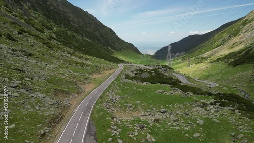 An aerial drone shot captures a female cyclist riding a bicycle on an asphalt road in the mountains, offering an amazing view. Cycling on the serpentine Transfagarasan road. Sport motivation.