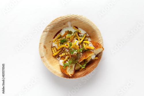 Top view of tasty'Aloo Chaat' or 'Aloo Tikki' (Indian Street Food) garnished with coriander leaves, red and white sauce. Isolated on a white background. photo