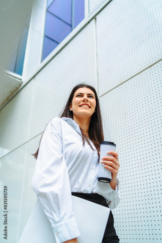 One young successful business woman going to work at business office modern building while holding coffee and papers One young successful business woman going to work at business office modern building while holding coffee and papers