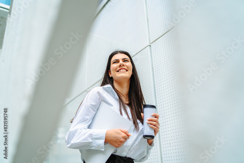 One young successful business woman going to work at business office modern building while holding coffee and papers Free Download One young successful business woman going to work at business office modern building while holding coffee and papers - GFXLoad