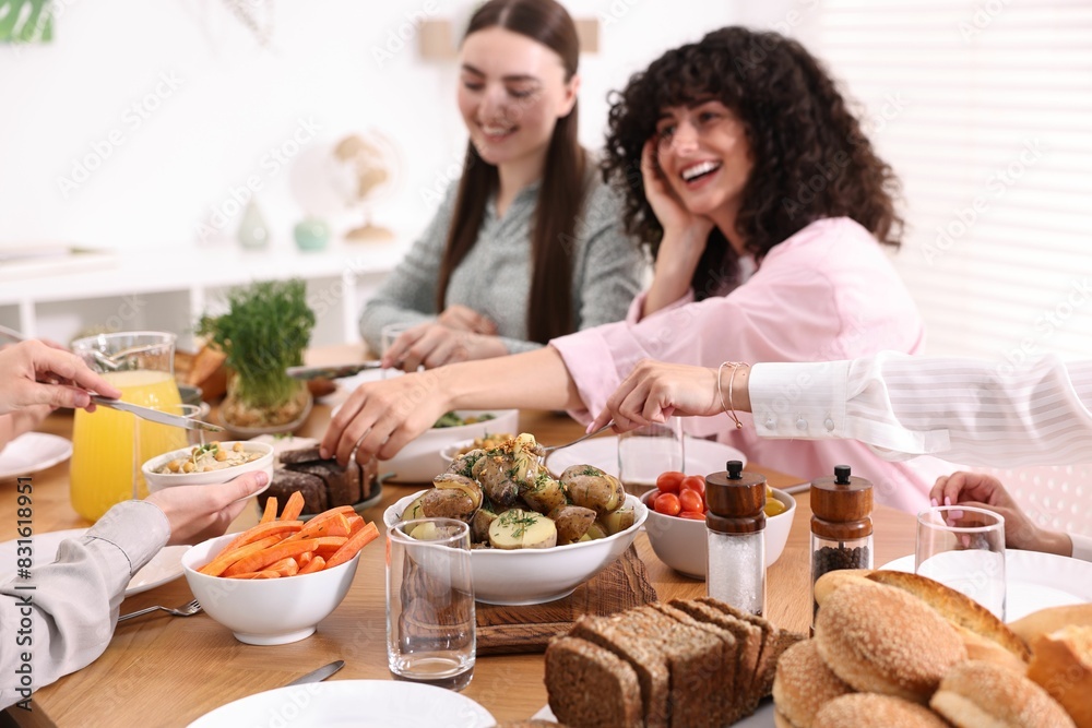 Friends eating vegetarian food at table indoors Friends eating vegetarian food at table indoors