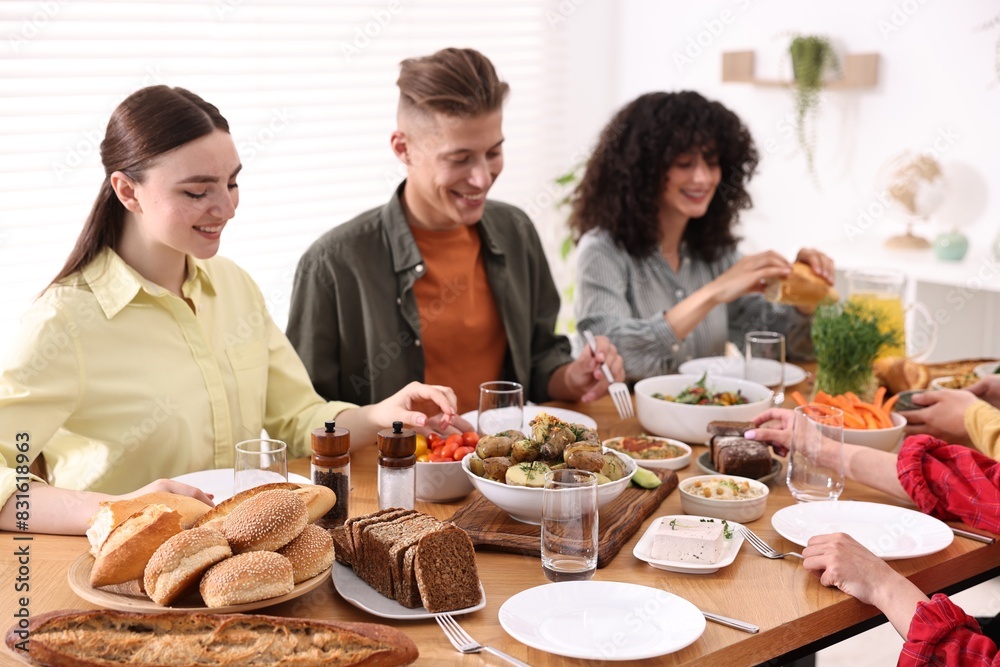 Friends eating vegetarian food at wooden table indoors Friends eating vegetarian food at wooden table indoors