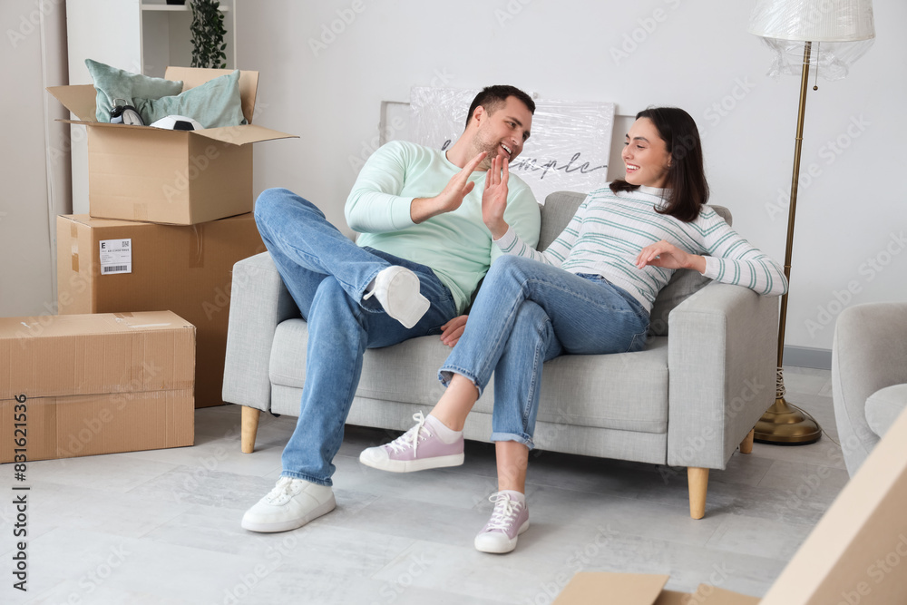 Happy young couple giving each other high-five in room on moving day