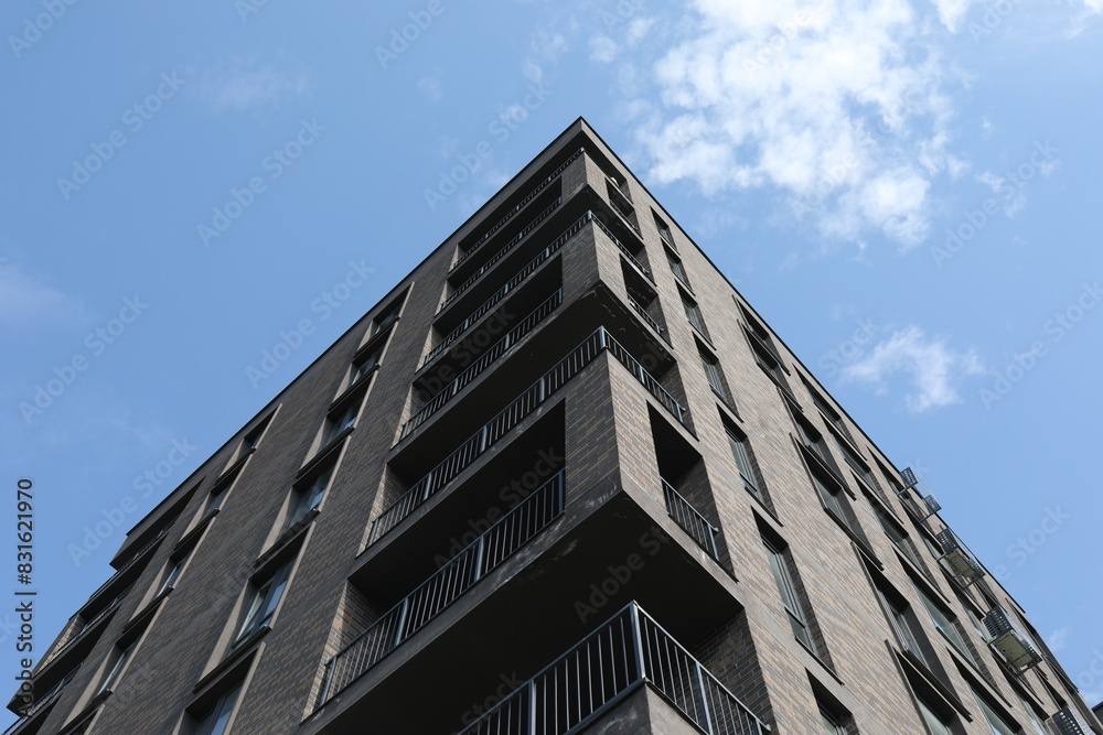 Modern building with big windows against blue sky outdoors, low angle view Modern building with big windows against blue sky outdoors, low angle view