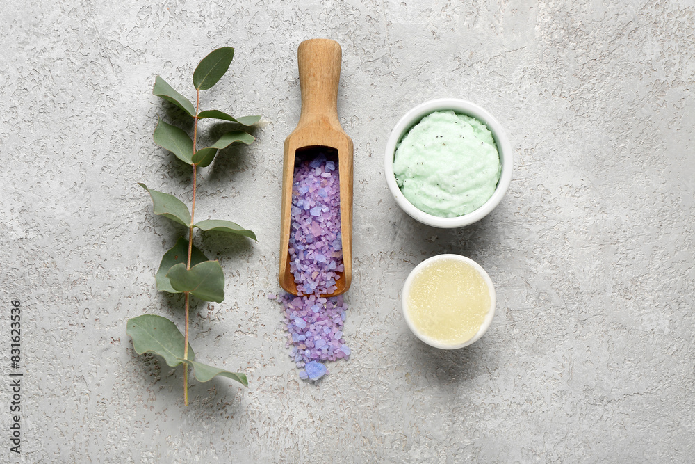 Bowls with body scrubs, sea salt and eucalyptus branch on grunge background