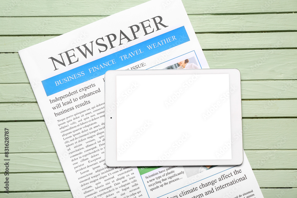 Newspaper with tablet on green wooden background Newspaper with tablet on green wooden background