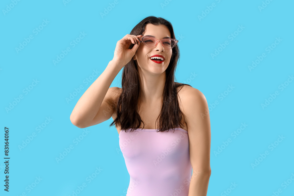 Beautiful young woman in swimsuit with sunglasses on blue background Beautiful young woman in swimsuit with sunglasses on blue background
