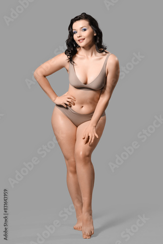 Beautiful young happy body positive woman in stylish underwear on grey background © Pixel-Shot