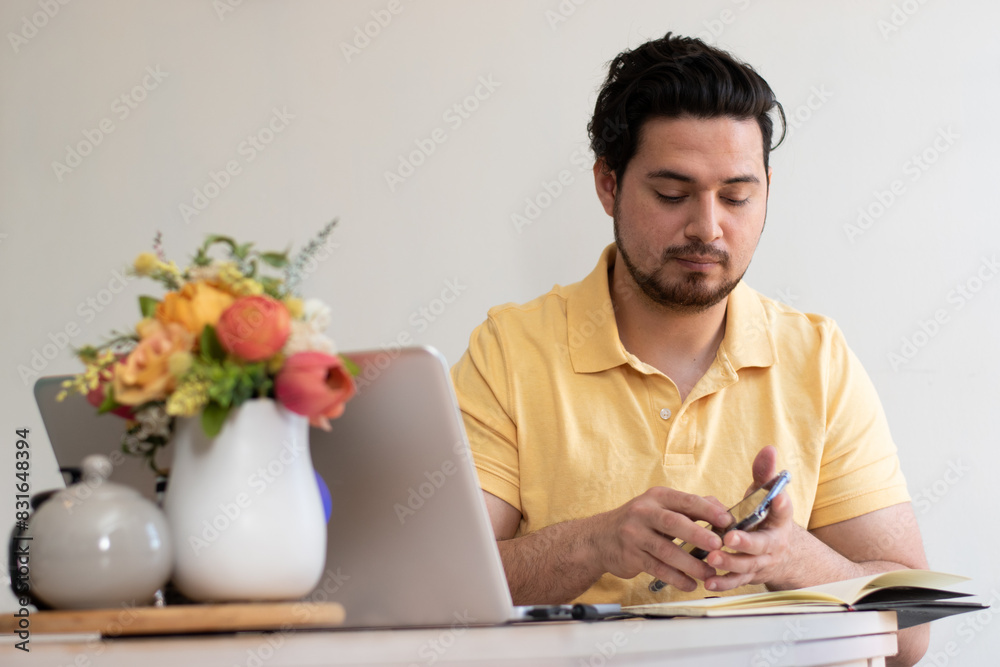 Young student with his note book front his laptop in the living room Young student with his note book front his laptop in the living room
