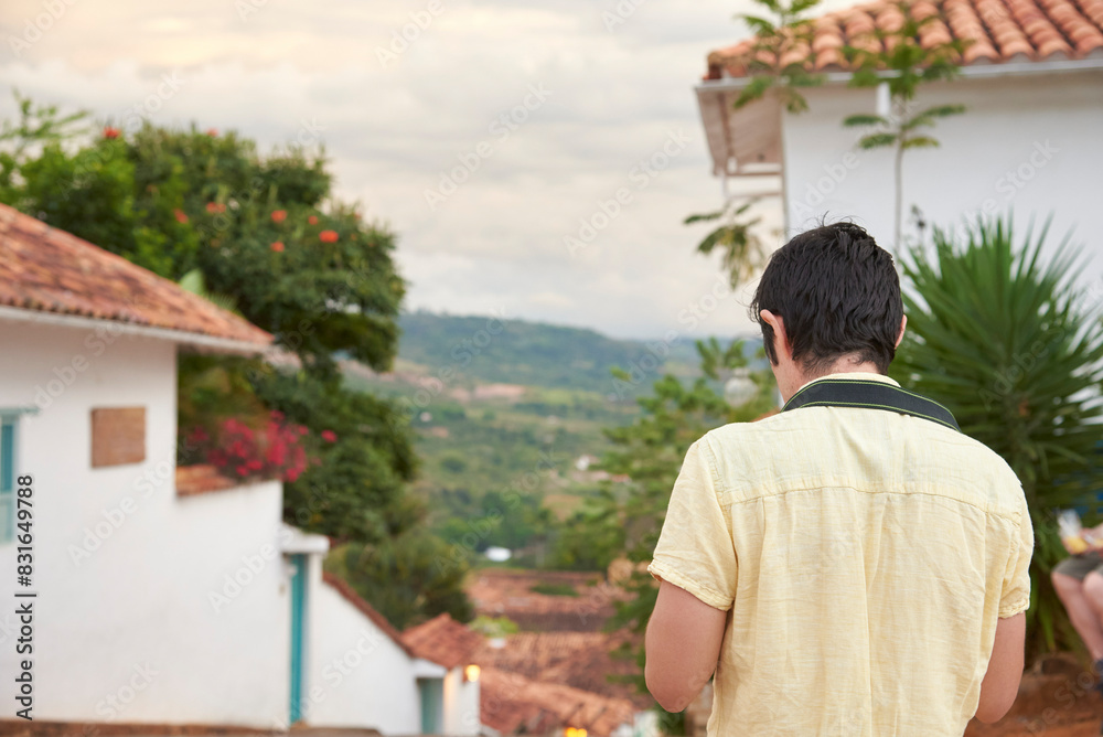 Unknown young man seen from behind walking and taking pictures in Barichara, touristic picturesque town declared a National Monument and known for being the most beautiful Colombian village. Unknown young man seen from behind walking and taking pictures in Barichara, touristic picturesque town declared a National Monument and known for being the most beautiful Colombian village.