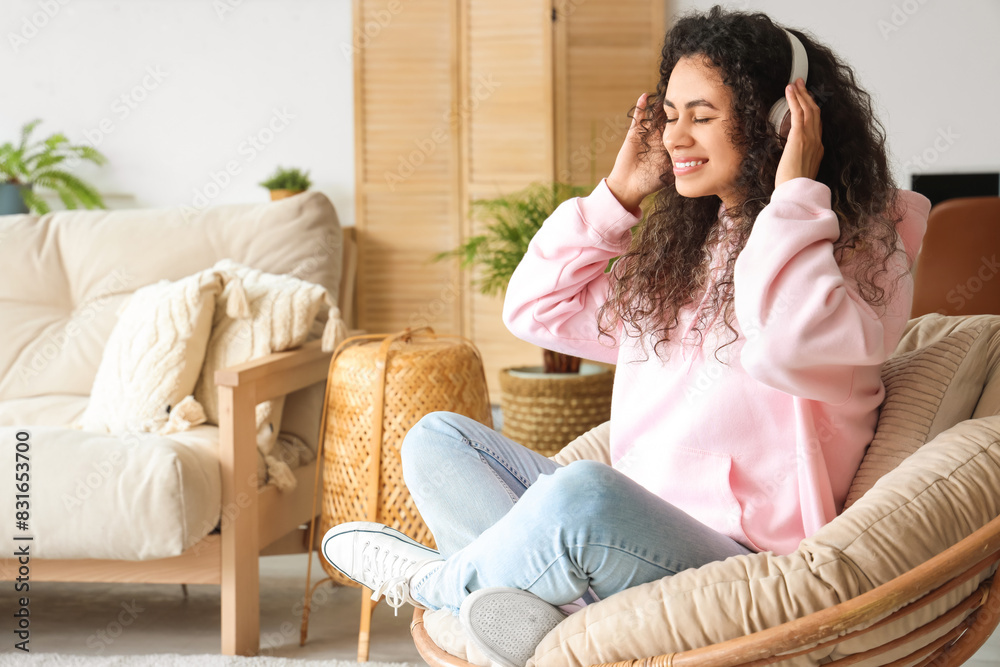 Young African-American woman with headphones resting in armchair at home Young African-American woman with headphones resting in armchair at home