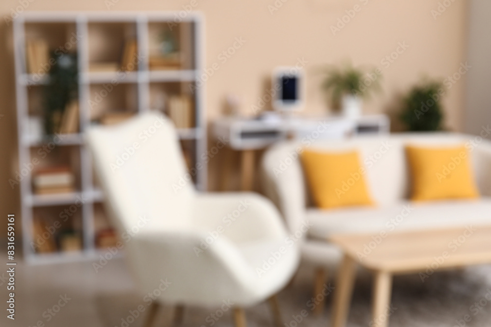 Interior of modern living room with sofa and bookshelf near beige wall, blurred view