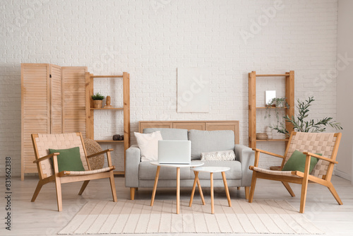 Beautiful interior of living room with grey sofa, armchairs, coffee table, shelving units and olive tree © Pixel-Shot