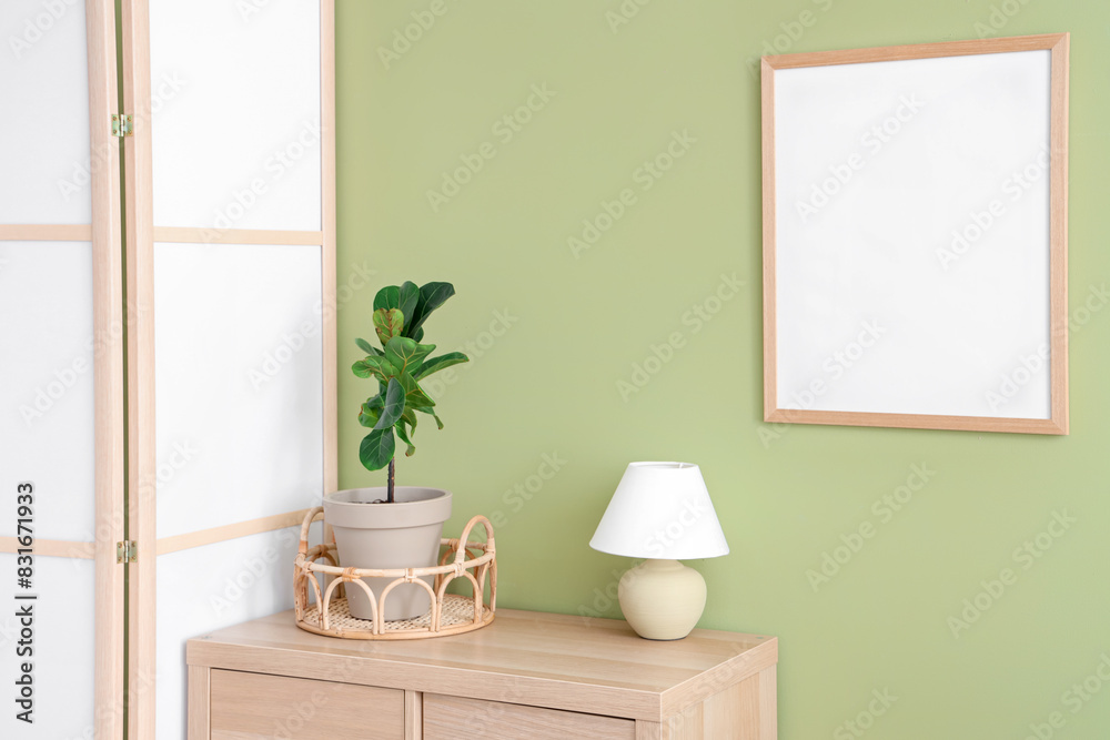 Interior of room with folding screen, commode and houseplant near green wall Interior of room with folding screen, commode and houseplant near green wall