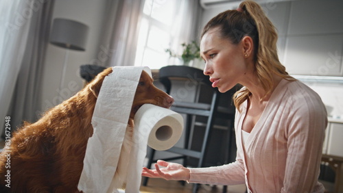 Tableau sur toile Girl punishing naughty pet chewing toilet paper in modern apartment close up